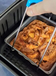 Gâteau aux pommes épicé en train d'être sorti de l'Air Fryer avec une pince