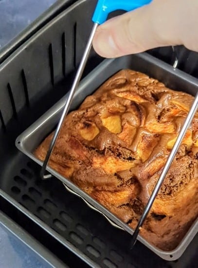 Gâteau aux pommes épicé en train d'être sorti de l'Air Fryer avec une pince